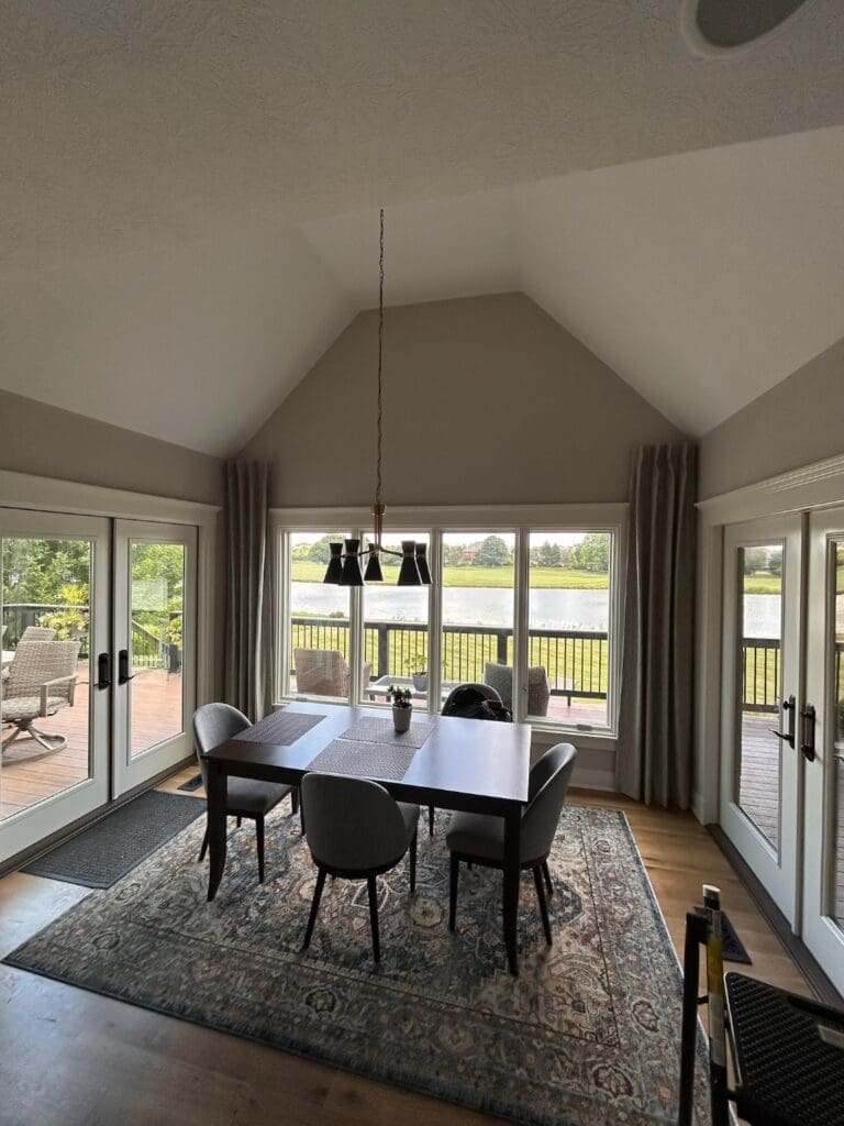InStyle Blinds IN - a dining room with large windows and a wrap-around deck has drapery panels for a cozy feeling.